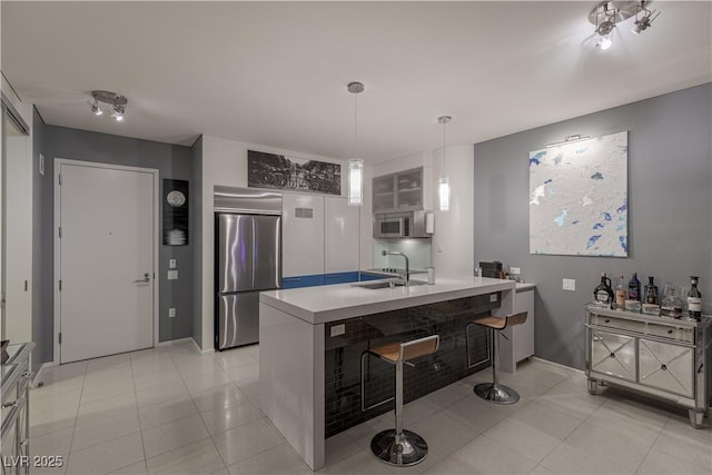 kitchen featuring built in fridge, light tile patterned flooring, sink, and white cabinetry