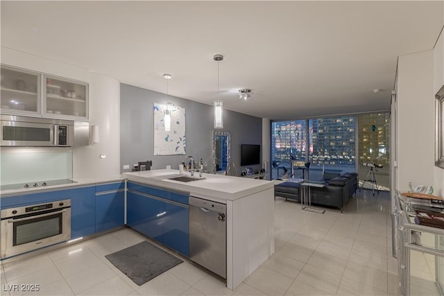 kitchen featuring stainless steel appliances, kitchen peninsula, sink, and light tile patterned floors