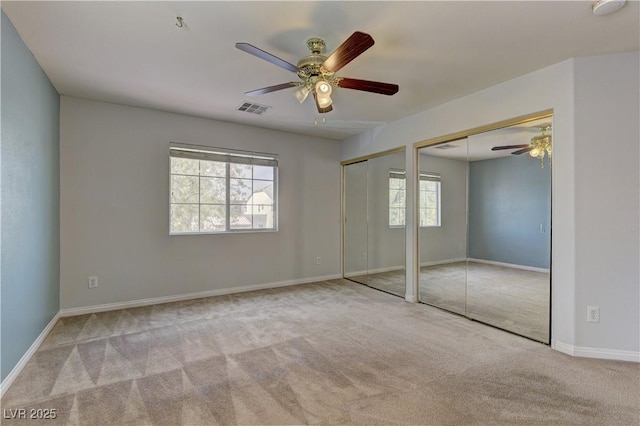 unfurnished bedroom with two closets, light colored carpet, and ceiling fan