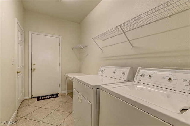 clothes washing area with light tile patterned floors and washing machine and clothes dryer