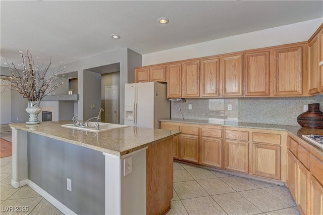 kitchen with tasteful backsplash, sink, white fridge with ice dispenser, light tile patterned floors, and light stone countertops