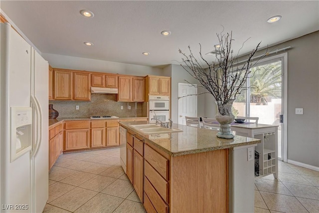 kitchen featuring white appliances, sink, an island with sink, and light tile patterned floors