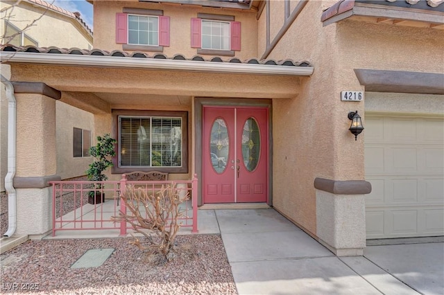 view of exterior entry with a garage and a porch