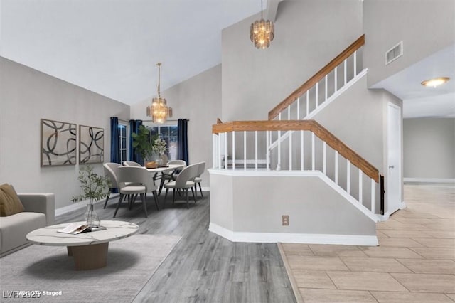 stairs featuring hardwood / wood-style floors, high vaulted ceiling, and a chandelier