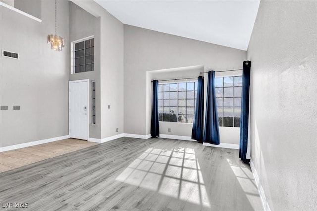 foyer featuring a notable chandelier, high vaulted ceiling, and light wood-type flooring