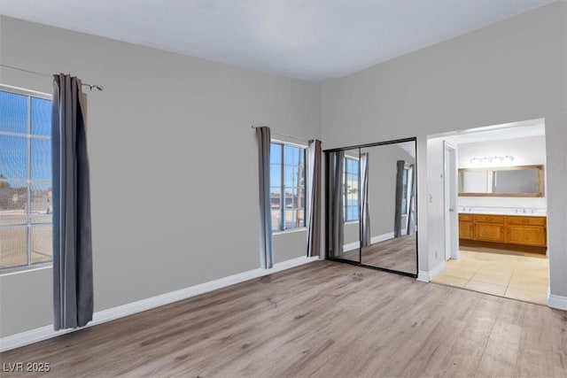 interior space with a closet, connected bathroom, and light hardwood / wood-style flooring