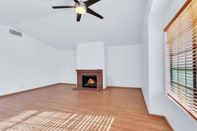 unfurnished living room with lofted ceiling, a fireplace, light hardwood / wood-style flooring, and ceiling fan