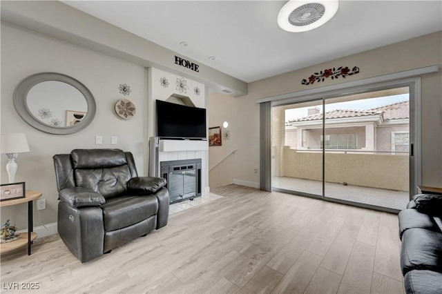 living room featuring a tile fireplace and light wood-type flooring