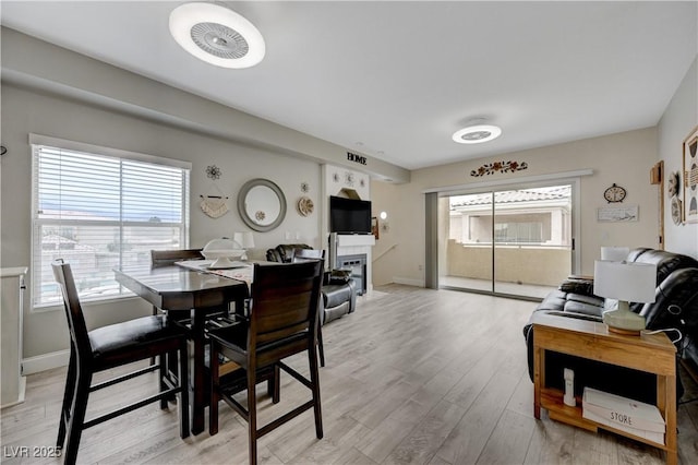 dining space with a tile fireplace and light wood-type flooring