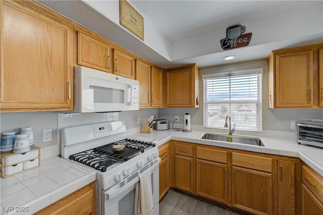 kitchen with sink, tile countertops, white appliances, and light wood-type flooring