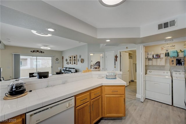 kitchen with white dishwasher, tile counters, separate washer and dryer, and light hardwood / wood-style flooring