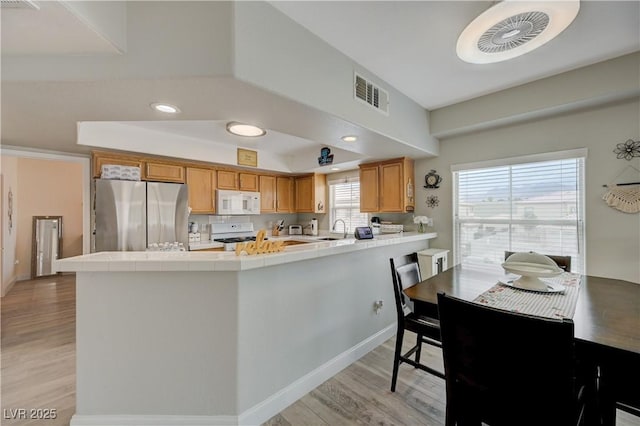 kitchen featuring white appliances, kitchen peninsula, and light wood-type flooring