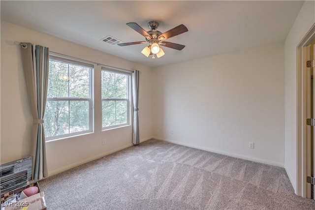 carpeted empty room featuring a ceiling fan, visible vents, and baseboards