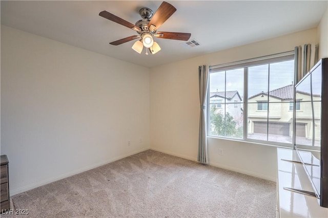 empty room with carpet flooring, baseboards, visible vents, and ceiling fan