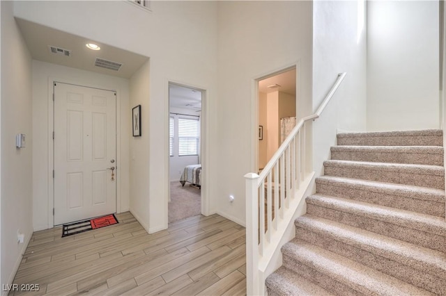 foyer entrance with stairway, baseboards, visible vents, and light wood-type flooring