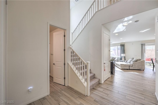 staircase with a high ceiling, baseboards, and wood finished floors