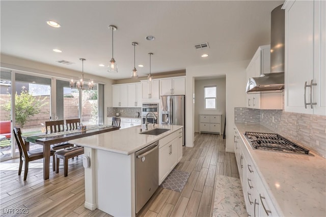 kitchen featuring visible vents, wood finish floors, a sink, white cabinets, and appliances with stainless steel finishes