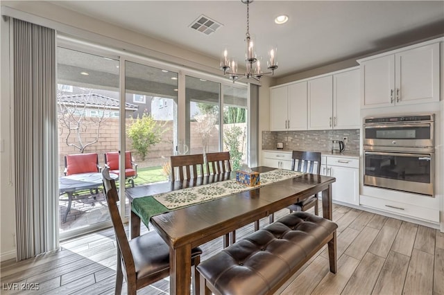 dining space with a notable chandelier, visible vents, recessed lighting, and wood tiled floor