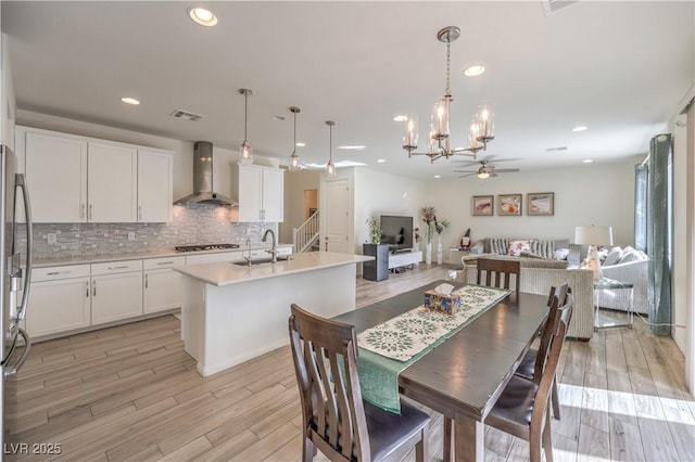 dining area with light wood finished floors, visible vents, ceiling fan with notable chandelier, and recessed lighting