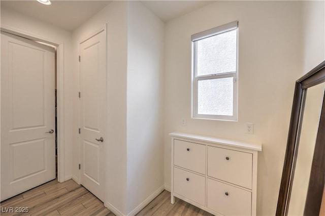 corridor featuring baseboards and light wood-style floors