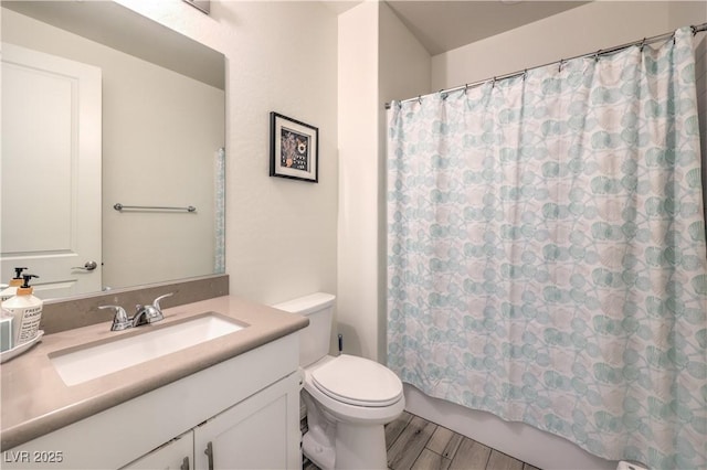 bathroom featuring shower / bath combo with shower curtain, toilet, vanity, and wood finished floors