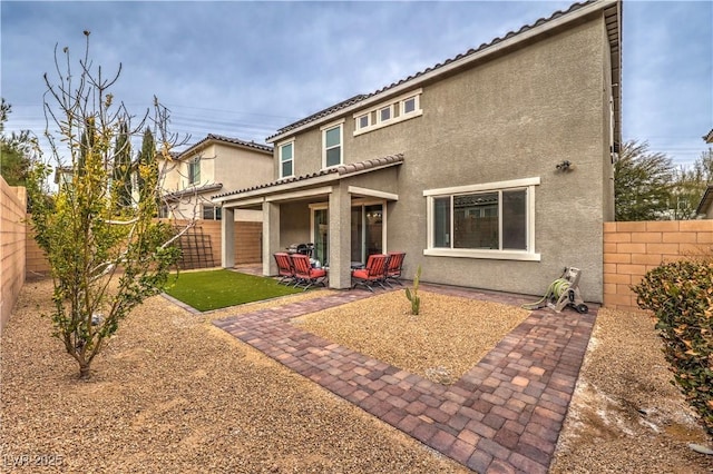 rear view of property featuring a fenced backyard, stucco siding, and a patio