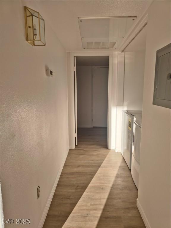 hallway with hardwood / wood-style floors, electric panel, and washer and clothes dryer