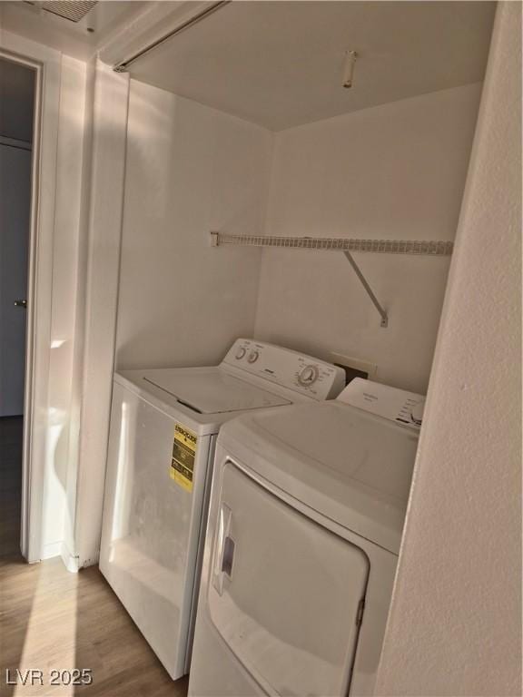 washroom featuring washer and clothes dryer and light hardwood / wood-style flooring