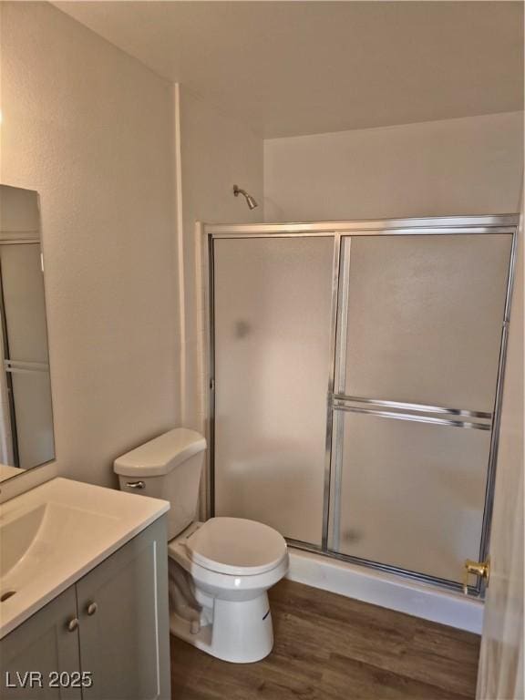 bathroom featuring vanity, toilet, a shower with door, and hardwood / wood-style floors