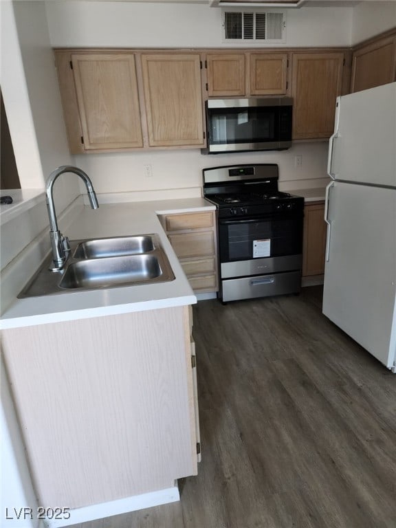 kitchen featuring sink, range with gas cooktop, light brown cabinets, white refrigerator, and dark hardwood / wood-style floors