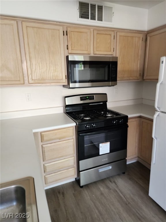 kitchen featuring white refrigerator, dark hardwood / wood-style flooring, light brown cabinetry, and range with gas cooktop