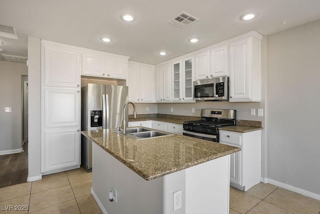 kitchen featuring sink, light tile patterned floors, white cabinetry, stainless steel appliances, and a center island with sink