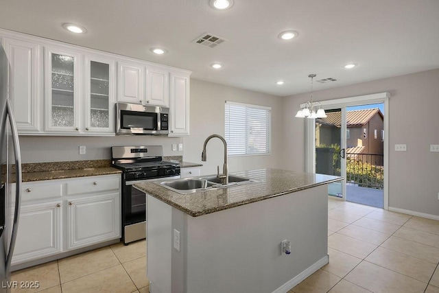 kitchen with sink, hanging light fixtures, an island with sink, stainless steel appliances, and white cabinets