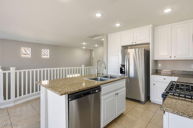 kitchen featuring stone countertops, an island with sink, sink, white cabinets, and stainless steel appliances