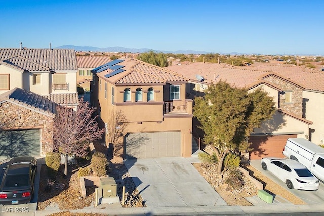 view of front of property with a garage, a balcony, a mountain view, and solar panels