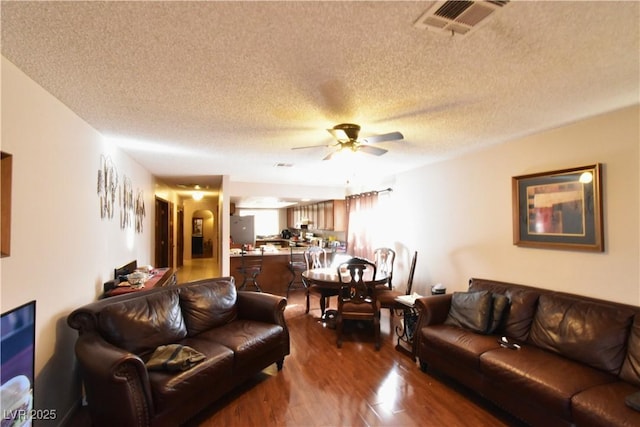 living room featuring ceiling fan, wood-type flooring, and a textured ceiling