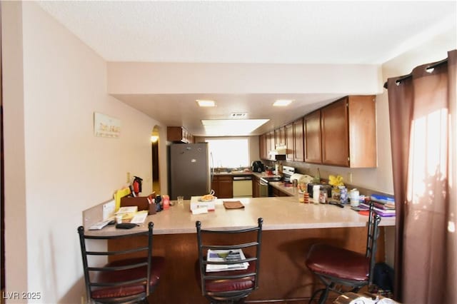 kitchen featuring stainless steel appliances, a kitchen breakfast bar, kitchen peninsula, and a textured ceiling