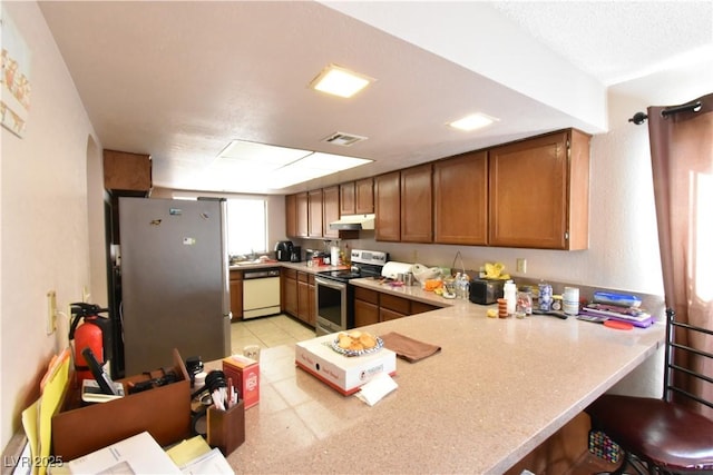 kitchen featuring a breakfast bar, appliances with stainless steel finishes, kitchen peninsula, and light tile patterned floors