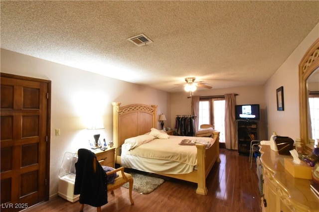 bedroom with dark wood-type flooring, a textured ceiling, and ceiling fan