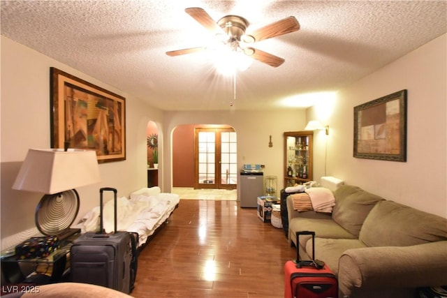 living room with ceiling fan, dark hardwood / wood-style floors, a textured ceiling, and french doors