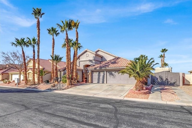 mediterranean / spanish-style house with concrete driveway, a gate, fence, a garage, and a tiled roof