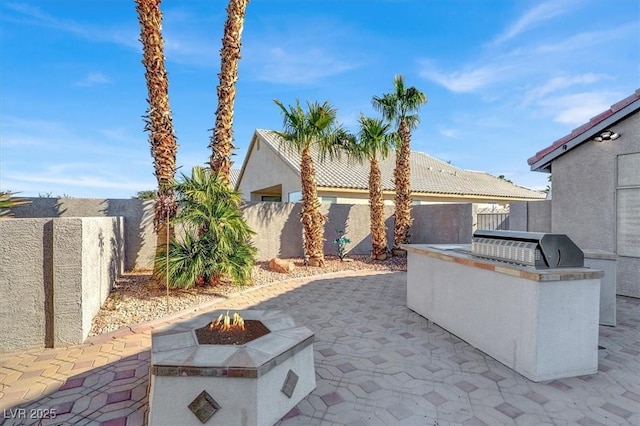 view of patio featuring area for grilling, a fire pit, and an outdoor kitchen