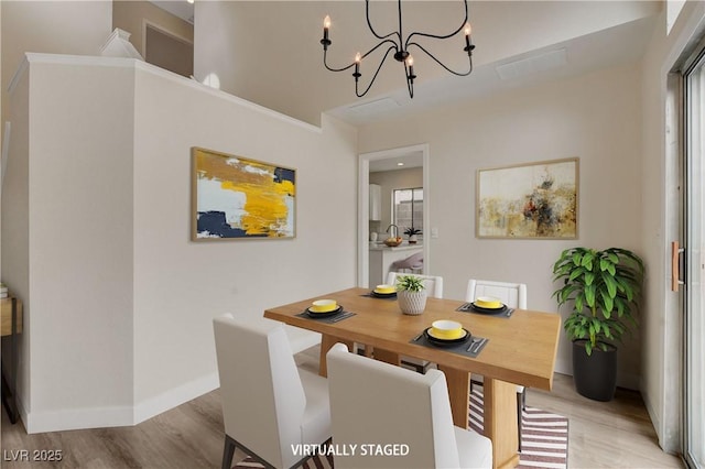 dining area with light wood-type flooring and an inviting chandelier