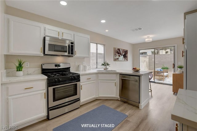 kitchen featuring white cabinetry, sink, stainless steel appliances, and light wood-type flooring