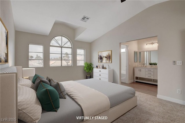 carpeted bedroom featuring lofted ceiling and connected bathroom