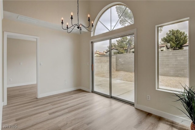 unfurnished dining area with light wood-type flooring and a chandelier