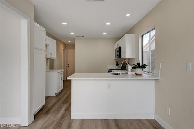 kitchen featuring sink, kitchen peninsula, and white cabinets