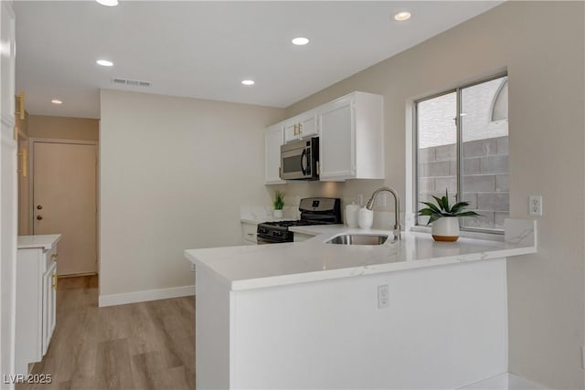 kitchen featuring stainless steel appliances, light hardwood / wood-style floors, sink, white cabinetry, and kitchen peninsula