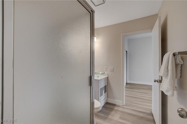 bathroom with hardwood / wood-style flooring, vanity, toilet, and walk in shower