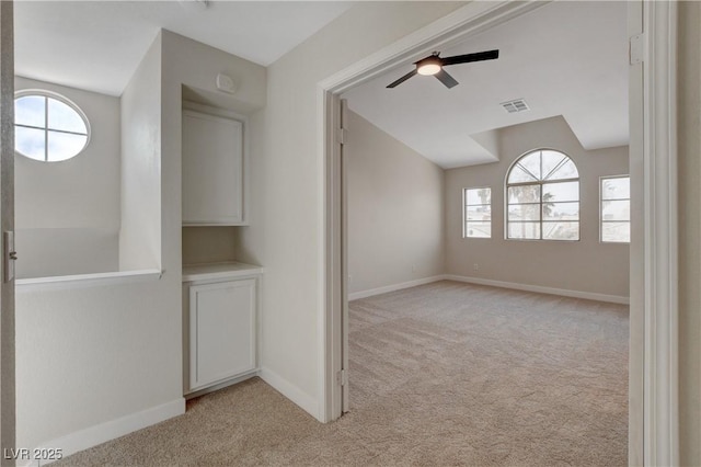 carpeted empty room featuring ceiling fan, vaulted ceiling, and plenty of natural light